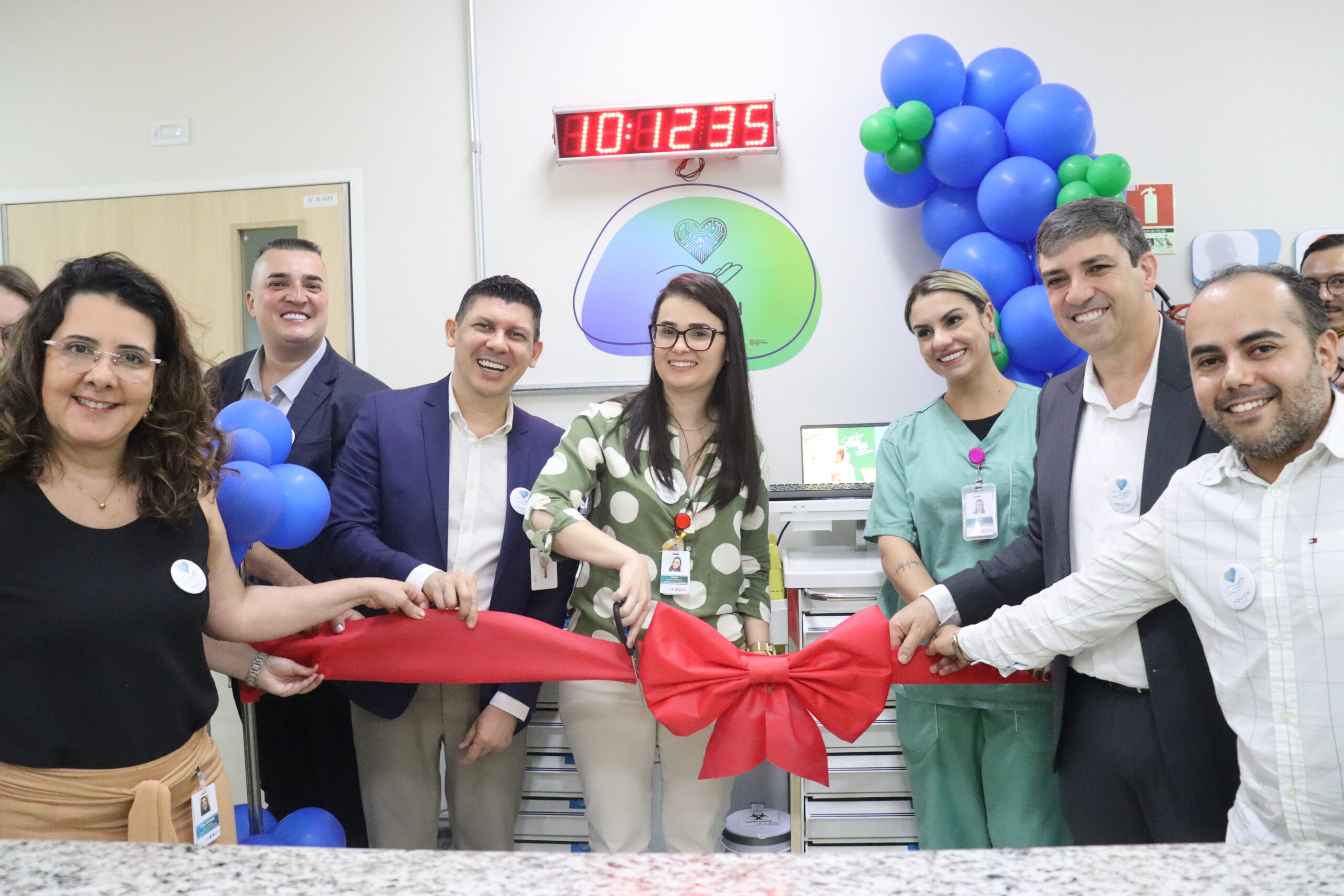 Equipe do Hospital Municipal da Brasilândia realiza inauguração do projeto Touch Care, cortando o laço simbólico durante a cerimônia de lançamento.